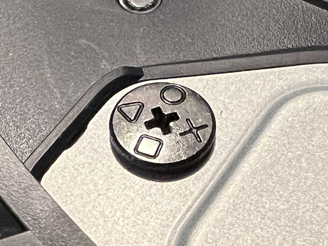 Stylized screw from within a PlayStation. It bears symbols from the faces of controller buttons